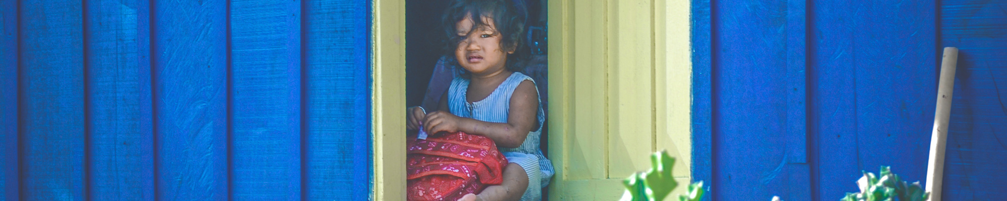petite fille assise devant une porte jaune entre ouverte